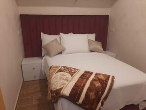 Cozy retreat with a single bed, nightstand, and bedside table, featuring a comfortable duvet and throw blanket.