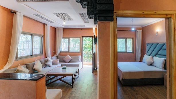 A hotel room with a sofa, a bed, a wooden floor, and a view of the outdoors. - Appartement Exceptionnel à Ourika (Marrakech)