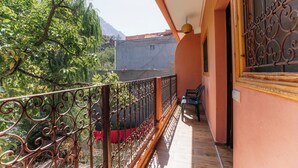 A balcony with a wrought iron railing, a table with chairs, and a view of a mountain and trees. - Appartement Exceptionnel à Ourika (Marrakech)
