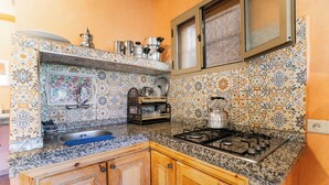 A kitchen with a sink, stove, and wooden cabinets. - Appartement Exceptionnel à Ourika (Marrakech)
