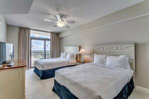Une chambre d’hôtel avec deux lits, un ventilateur de plafond, une télévision et une vue sur les montagnes.