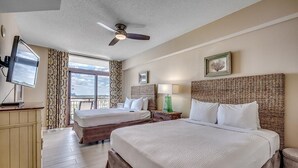 Une chambre d’hôtel avec deux lits, un ventilateur de plafond, une télévision et une grande fenêtre donnant sur un beau paysage.