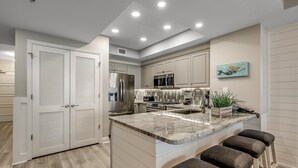 Una cocina moderna con una isla central, electrodomésticos integrados y una zona de estar con taburetes de bar.