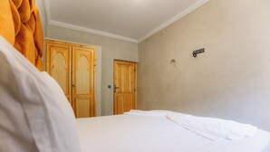 A bedroom with a bed, wooden wardrobe, and a small wall-mounted light fixture. - Premier Appartement Ourika (Marrakech)