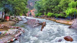A river with rocks and a building in the background. - Premier Appartement Ourika (Marrakech)