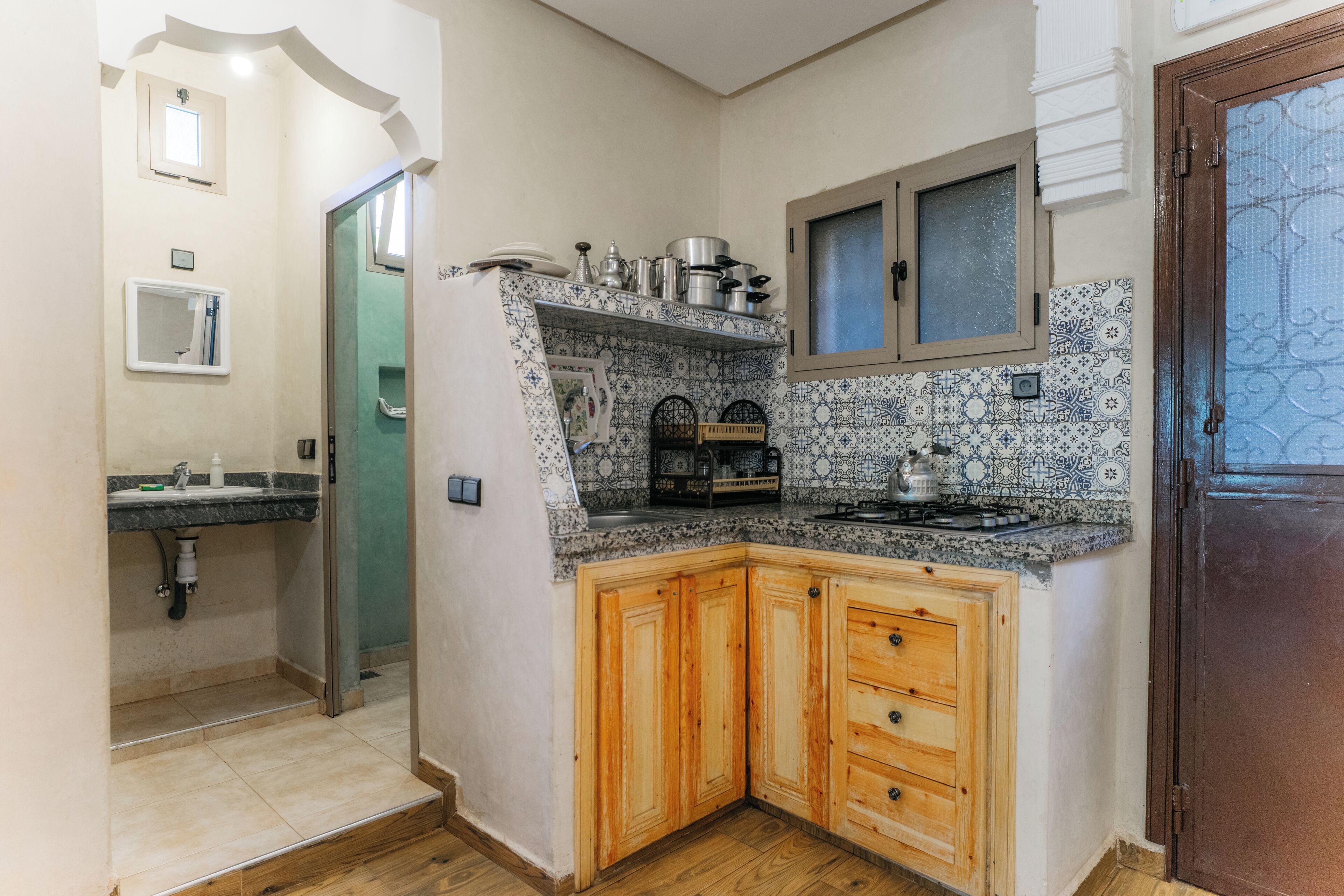 Et kompakt køkken med indbygget komfur, træskabe og et mønstret backsplash af fliser.