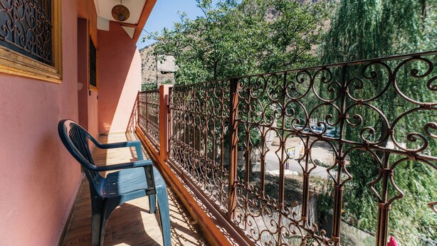 A balcony with a wrought iron railing, a plastic chair, and a view of a mountainous landscape. - Premier Appartement Ourika (Marrakech)