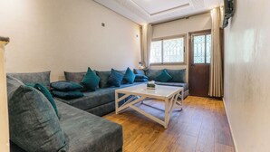 A living room with a sectional sofa, a coffee table, and a wooden floor. - Premier Appartement Ourika (Marrakech)