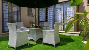 A patio with a table and chairs, a green umbrella, and a potted plant. - Nairobi's Oasis: Pool, Gym, & Modern Comforts (Nairobi)