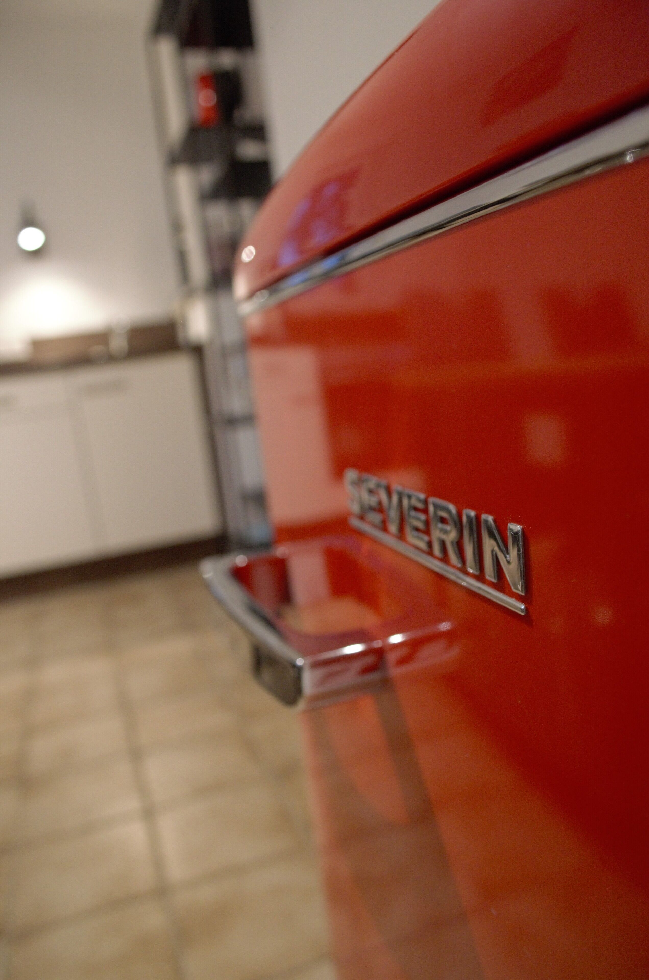 Une vue rapprochée d’une voiture rouge ancienne, sur laquelle on peut lire le mot « SEVERIN » sur le côté.