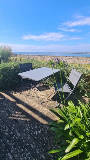 Une terrasse extérieure avec une table et deux chaises, offrant une vue sur la côte.