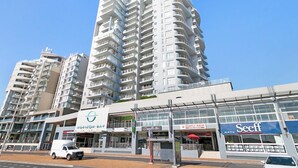 Un moderno grattacielo con numerosi balconi, un ristorante in vista e un negozio Seeff.