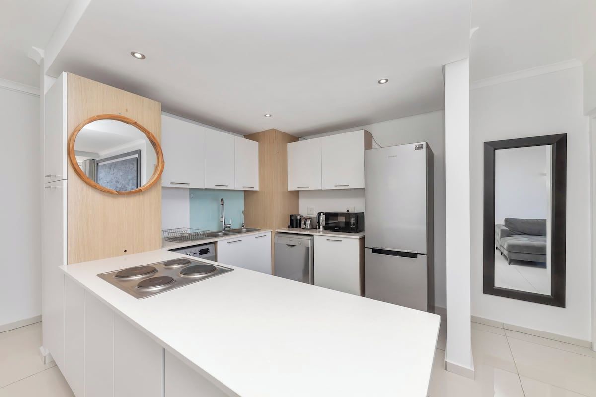 A modern kitchen with white cabinetry, a central island with a stove, and a microwave.