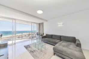 Un moderno salón con un amplio ventanal, un sofá gris y una mesa de centro de vidrio.