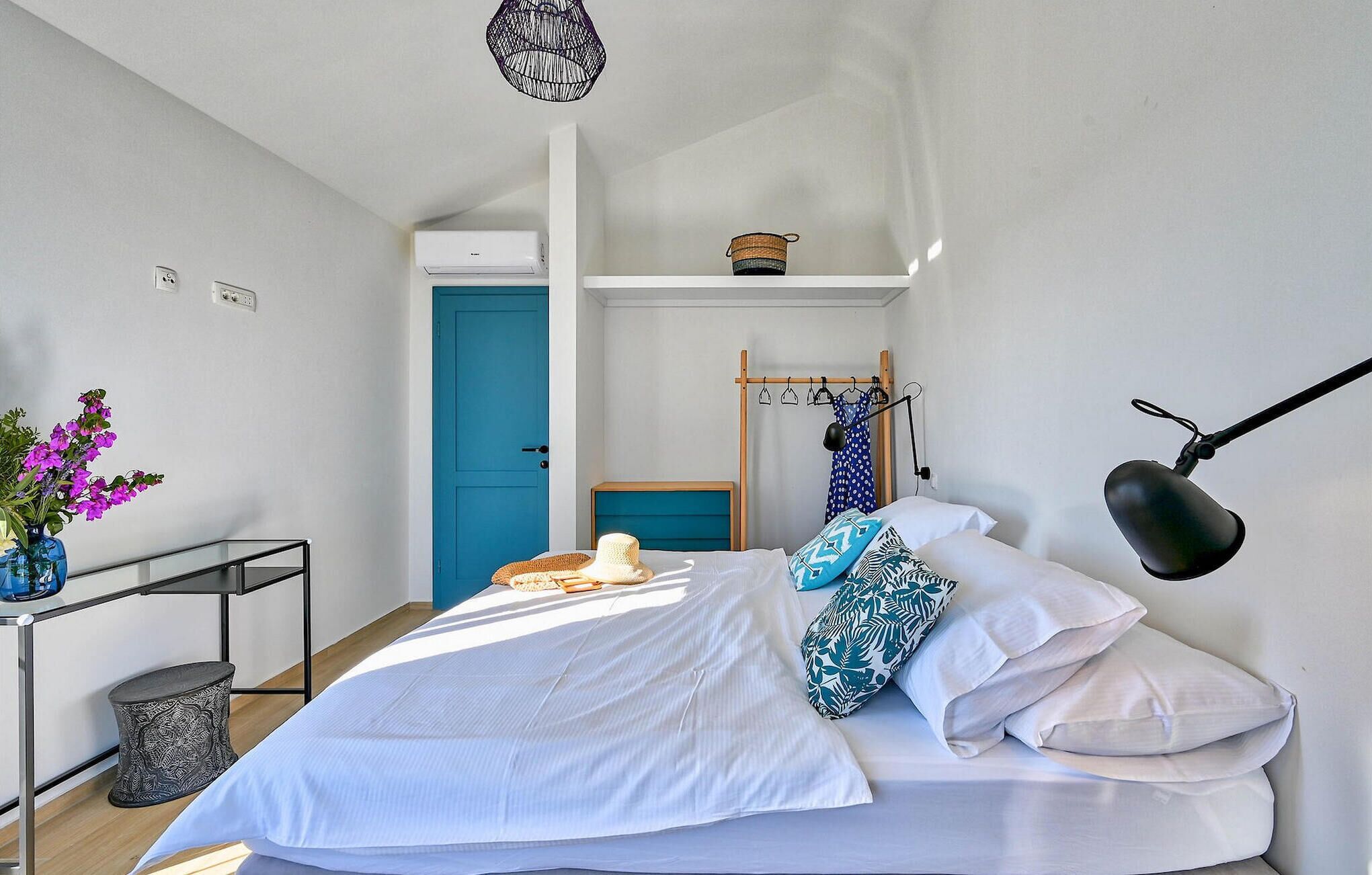 A bedroom with a bed, a bedside table, a lamp, a wardrobe, and a door.