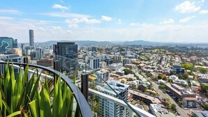 A high-rise building with a view of a cityscape, including various buildings and a distant mountain range. - City Living! 1Bed/1Bath/Pool (Brisbane City)