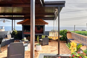 An outdoor patio with wicker furniture, a tiled floor, and a view of the ocean. - Casa Primavera, a Home in Madeira (Ponta do Sol)