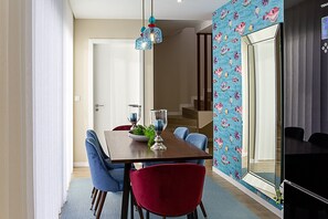A dining area with a wooden table, blue and red chairs, and a hanging light fixture. - Quinta do Feliz, a Home in Madeira (Ponta do Sol)
