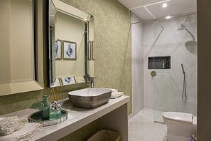 A modern bathroom with a large mirror, a vessel sink, a glass shower enclosure, and a toilet. - Quinta do Feliz, a Home in Madeira (Ponta do Sol)