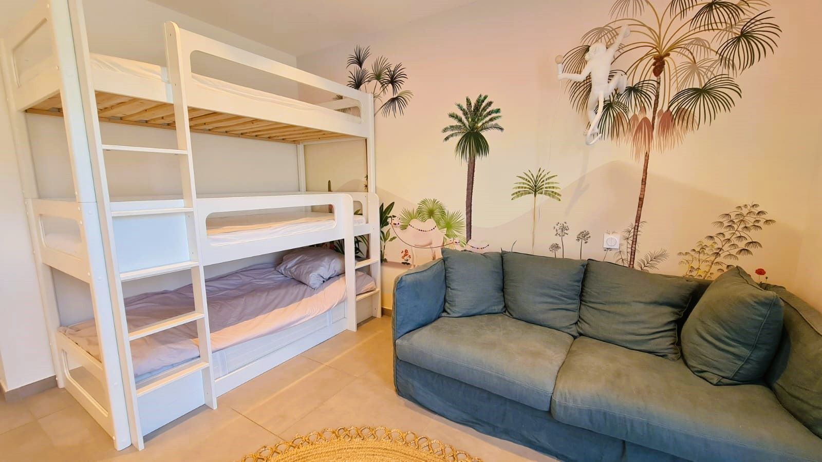 A room with a bunk bed, a sofa, and a wall mural.