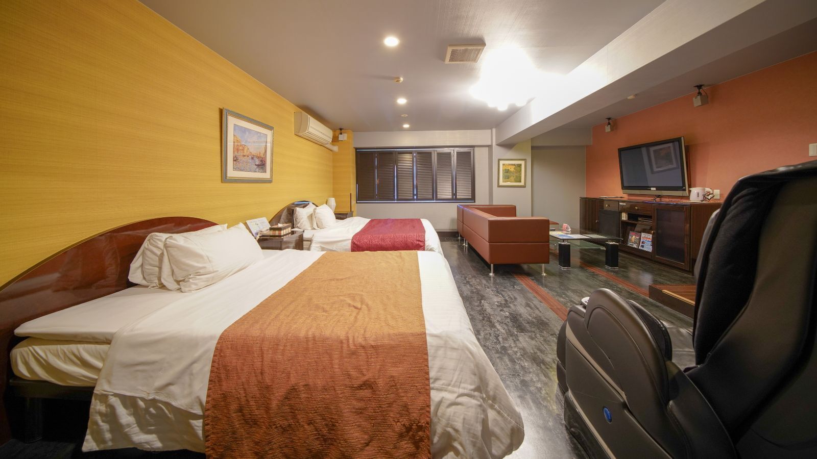 Une chambre d’hôtel avec deux lits, un canapé, une télévision et un bureau avec un ordinateur.