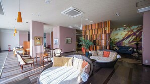 A modern hotel lobby with a round bed, seating area, and a decorative wall with vertical panels. - HOTEL LAVIEN (Togitsu)