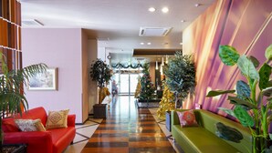 A hotel lobby with a checkered floor, red and green sofas, and large potted plants. - HOTEL LAVIEN (Togitsu)