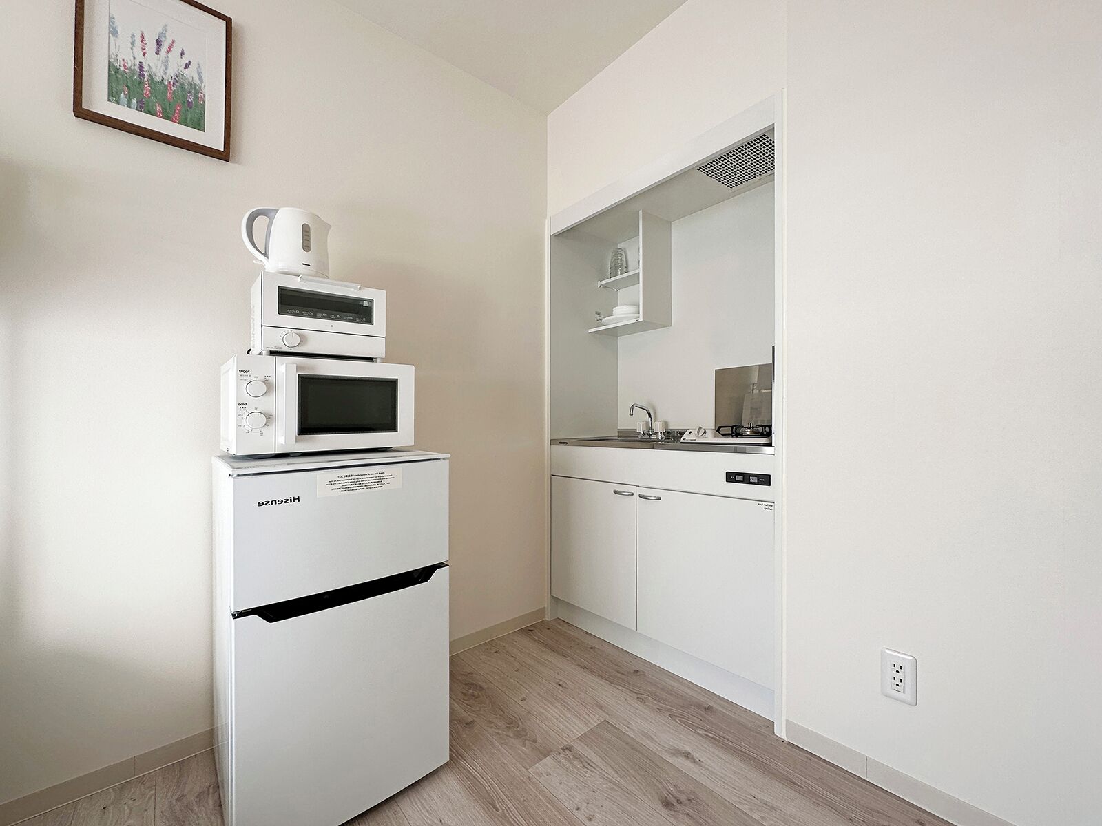 A compact kitchenette with a built-in microwave, oven, and coffee maker on a white refrigerator.
