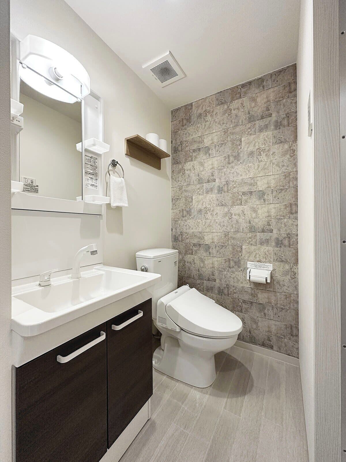 Un baño moderno con lavamanos blanco, inodoro y zona de ducha.