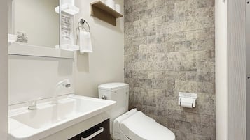 Un baño moderno con lavamanos blanco, inodoro y zona de ducha.