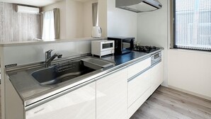 A modern kitchen with a stainless steel sink, a built-in oven, a microwave, and a gas stove. - Yutori (Onomichi)