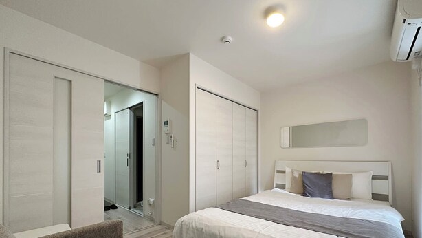 A hotel room with two beds, a sofa, a wardrobe, and a mirror. - Yutori (Onomichi)