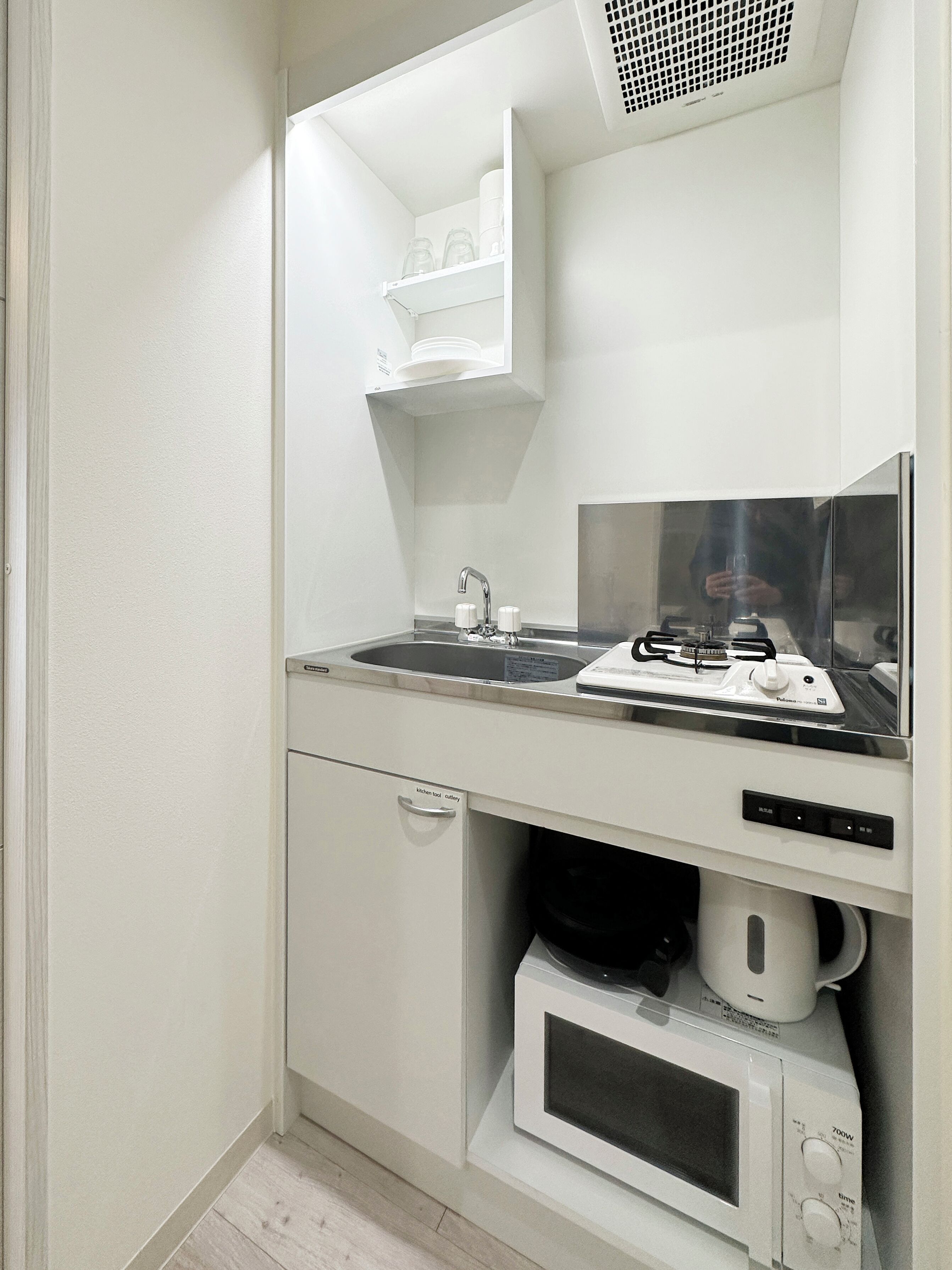 A compact kitchenette with a built-in microwave, a sink with a faucet, and a small cabinet below the counter.