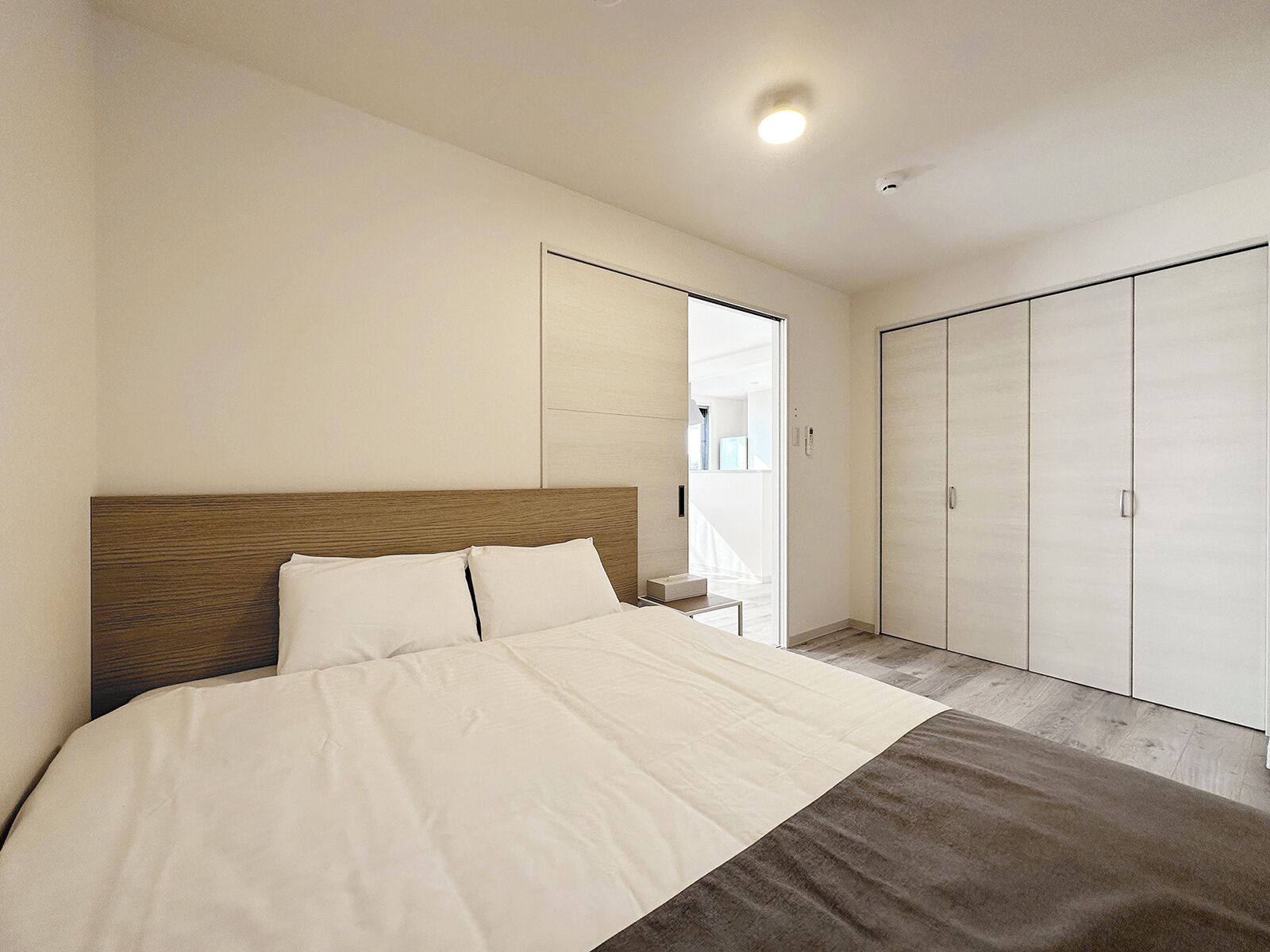 Une chambre à coucher avec un grand lit, une tête de lit en bois, une armoire et une petite table de chevet.