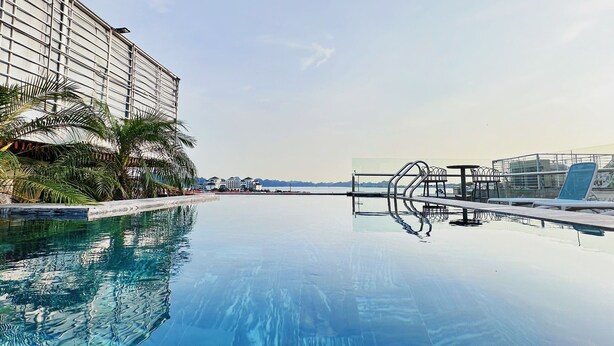 A clear swimming pool with a modern design, surrounded by palm trees and a large building. - Green Suites Hotel Ha Long (Bai Chay)