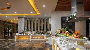A modern hotel lobby with a marble floor, a reception desk, and a buffet area with various food items and a coffee station. - Green Suites Hotel Ha Long (Bai Chay)