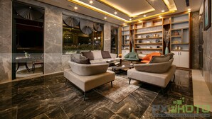 A modern living room with a marble floor, a sofa set, a coffee table, and a bookshelf with decorative items. - Green Suites Hotel Ha Long (Bai Chay)