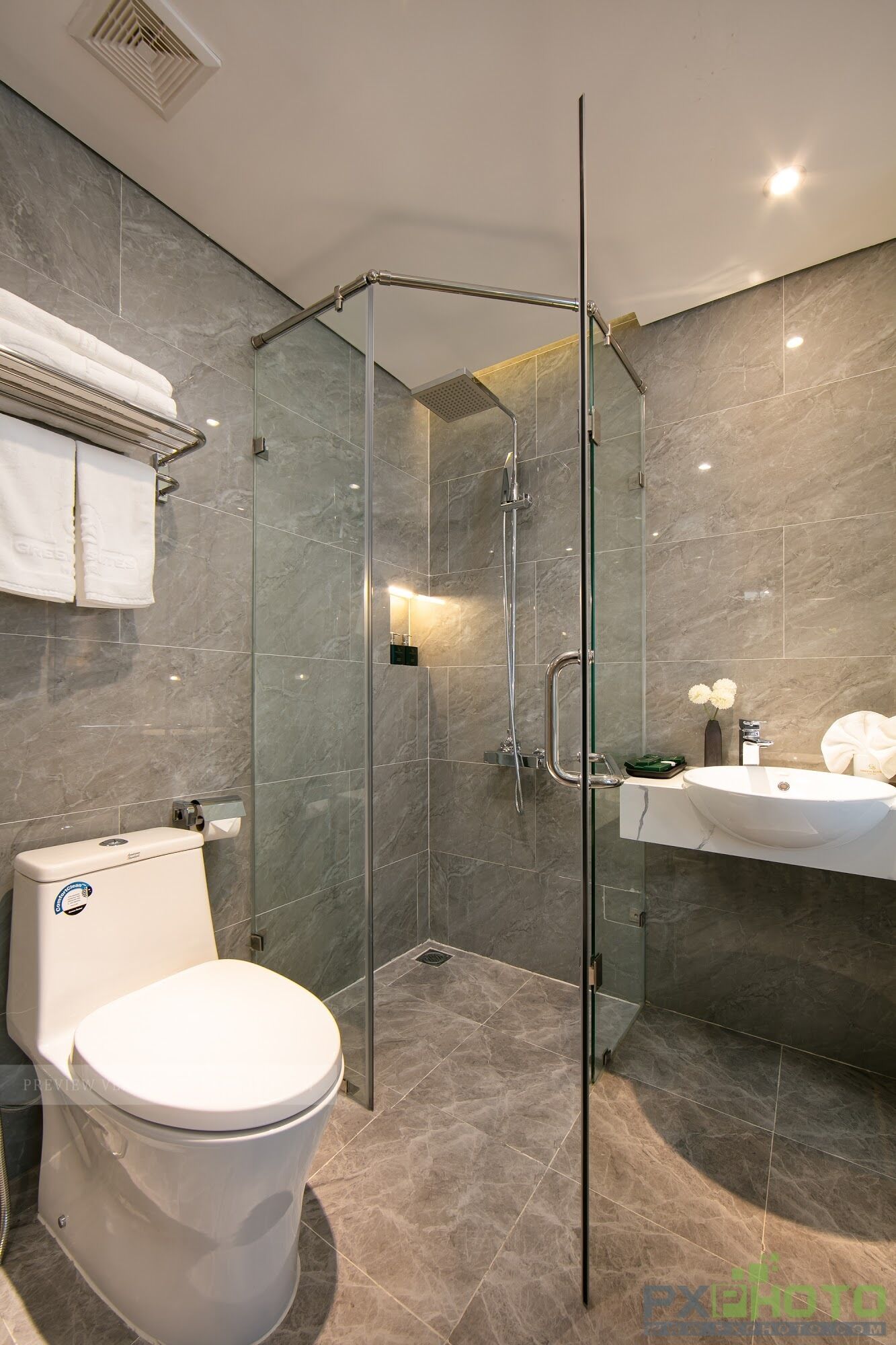 A modern bathroom with a glass-enclosed shower, a white toilet, and a vanity with a sink and mirror.