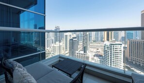 A high-rise balcony with a city view, furnished with a sofa and a small table. - Premium 2BR Apt w/ Marina Views (Dubai)