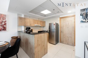Une cuisine moderne avec des meubles en bois, un réfrigérateur en acier inoxydable et une machine à café.