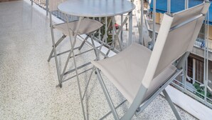 A balcony with a round table and two chairs, overlooking a cityscape with buildings and a clear sky. - Modern Family Apartment near Acropolis (Athens)