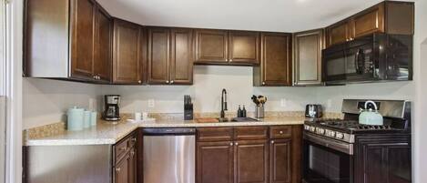 Een koelkast, een vaatwasser, kookgerei, borden en bestek, keukenpapier