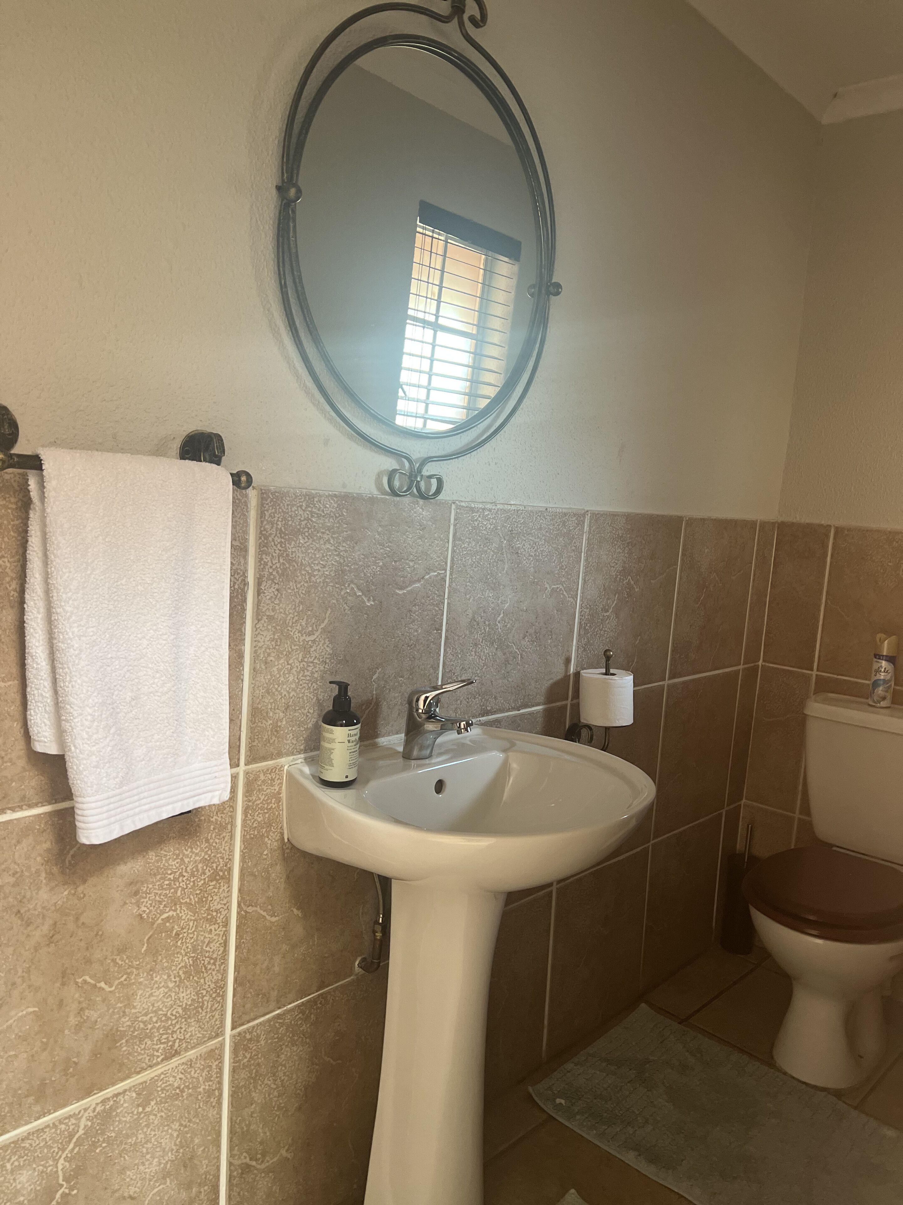 A bathroom with a white sink, a mirror, a towel rack, and a toilet.