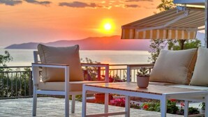 A terrace with two white chairs and a table, overlooking a sunset over water. - Seaview Villa Lavanda with pool (Drobnici)