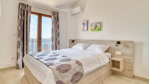 A bedroom with a bed, a nightstand, a window with curtains, and two wall-mounted artworks. - Seaview Villa Lavanda with pool (Drobnici)