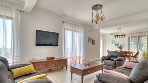 A modern living room with a sofa set, a coffee table, and a TV mounted on the wall. - Seaview Villa Lavanda with pool (Drobnici)