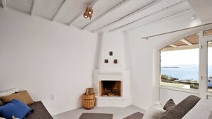 Una sala de estar moderna con chimenea, un conjunto de sofás y un amplio ventanal con vistas al mar.
