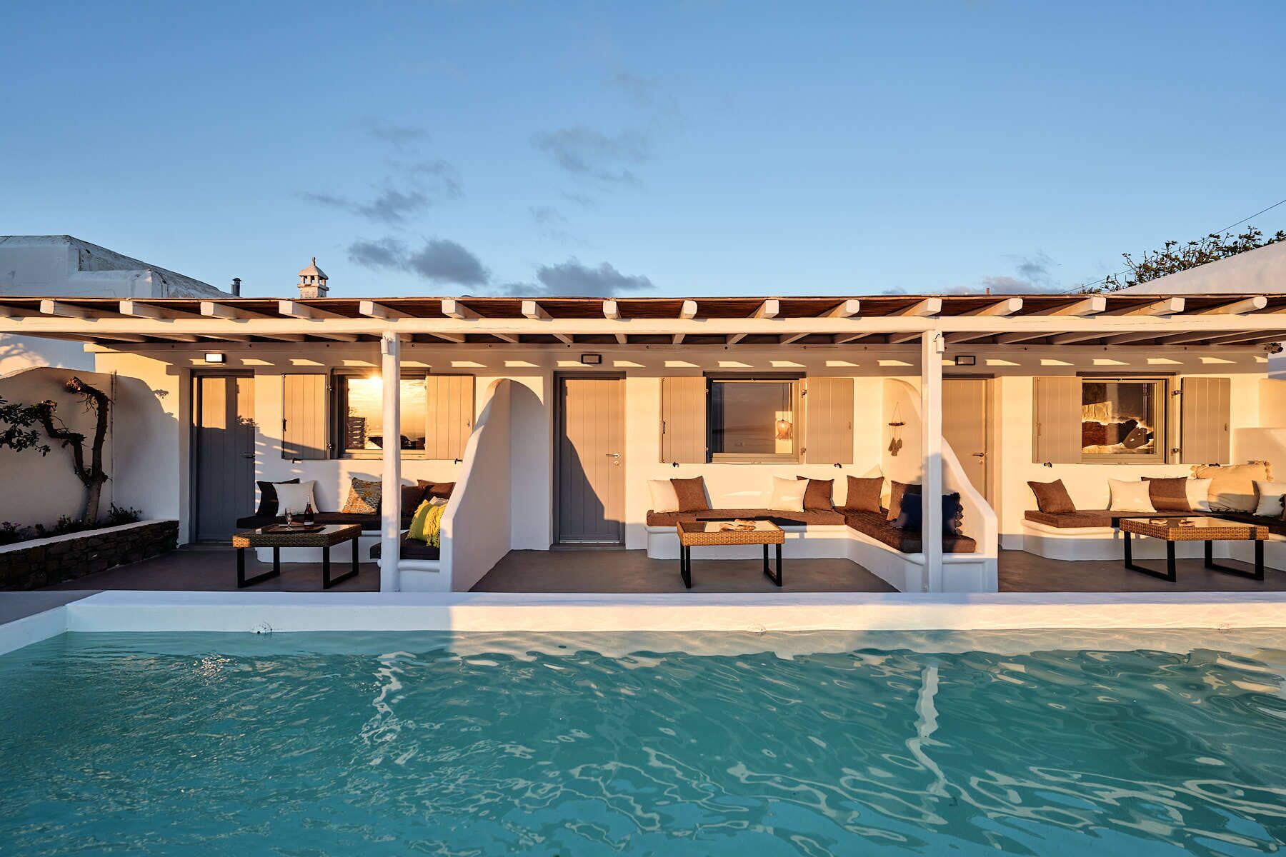 A poolside area with a covered seating area, a pool, and a building with large windows and doors.