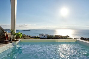 Ein Pool mit Blick auf das Meer und Gebäude im Hintergrund.