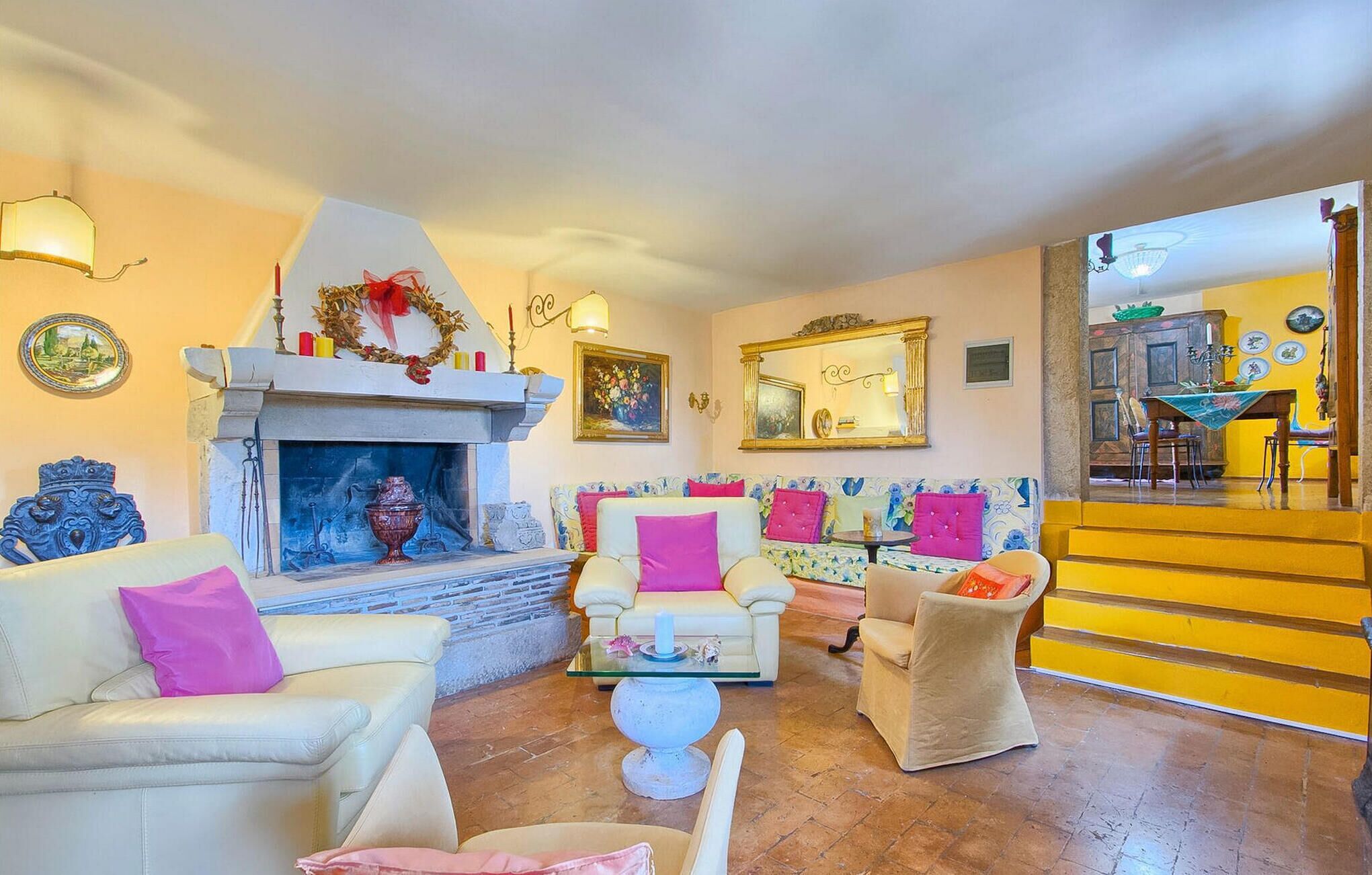 A living room with a fireplace, sofas, and a dining area with yellow walls.
